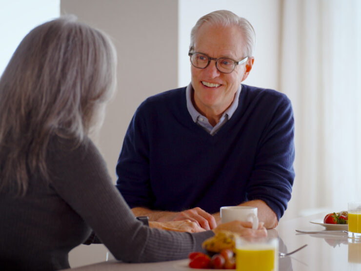 Two seniors enjoy a warm conversation over breakfast in a bright, inviting dining area.