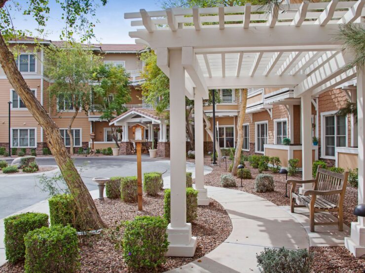 Outdoor seating area with shaded walkway and well-maintained landscaping in a welcoming community setting.