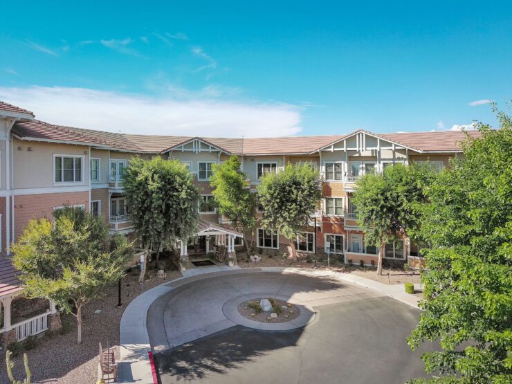 A bright, welcoming retirement community with shaded walkways and lush greenery.