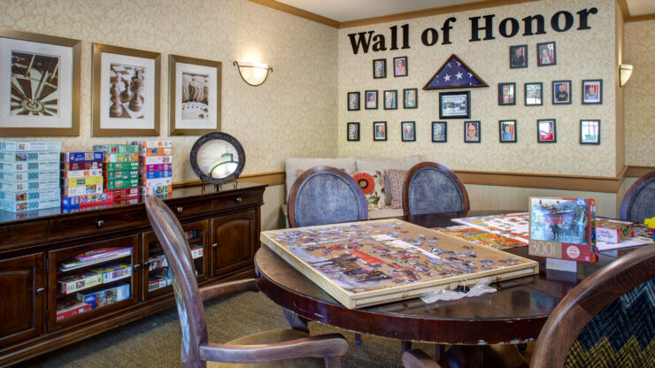 Bright activity room with puzzles, games, and a Wall of Honor celebrating community members.