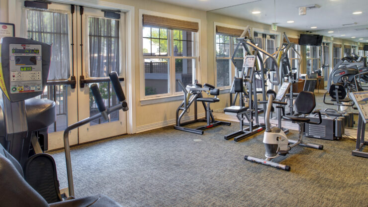 Bright exercise room with modern fitness equipment and large windows for natural light.