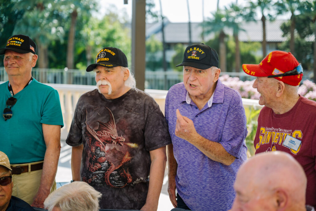 Active veterans sharing stories and laughter outdoors in a friendly retirement community.