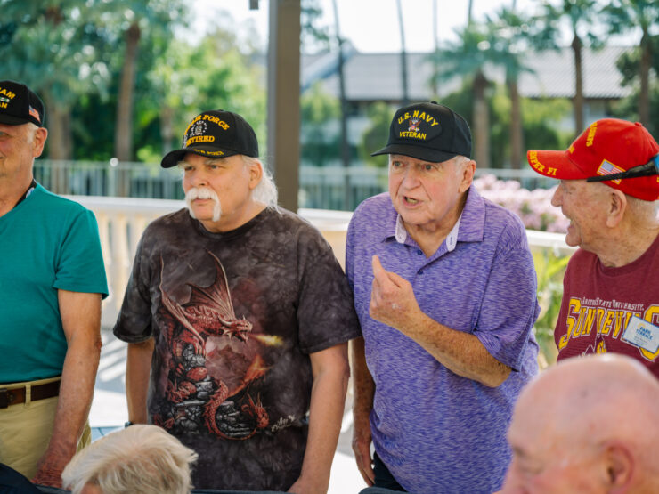 Active veterans sharing stories and laughter outdoors in a friendly retirement community.