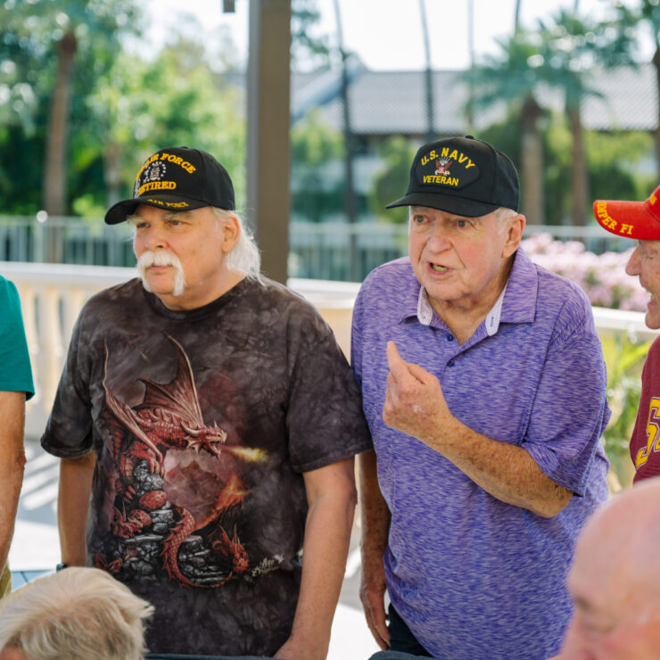 Active veterans sharing stories and laughter outdoors in a friendly retirement community.
