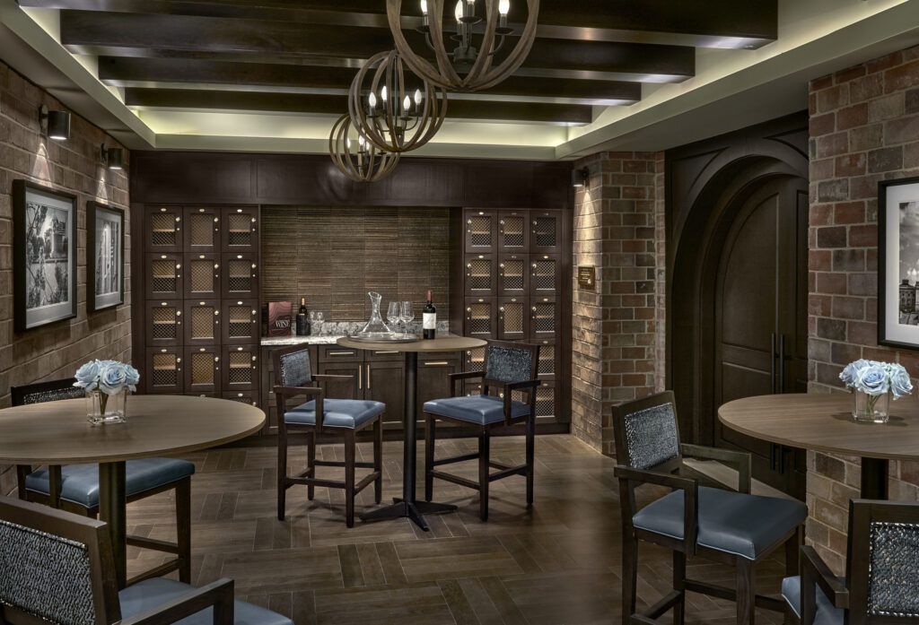 Warm, inviting lounge with elegant lighting, comfortable seating, and a welcoming wine display.