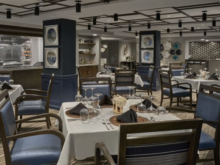 Dining room with elegant table settings and open kitchen, designed for community comfort and connection.