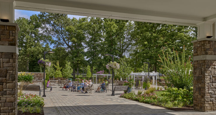 Residents enjoying an outdoor activity session surrounded by trees and vibrant gardens.