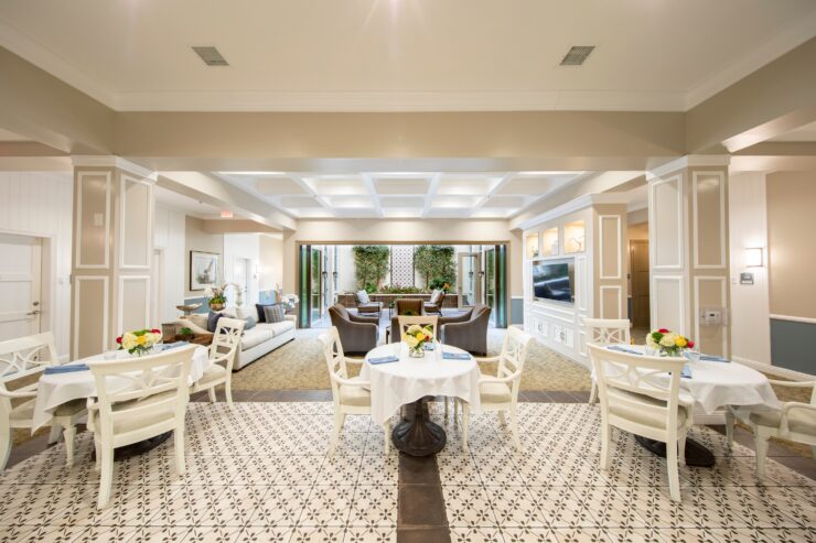 Bright communal dining and seating area with fresh flowers and open access to a garden patio.