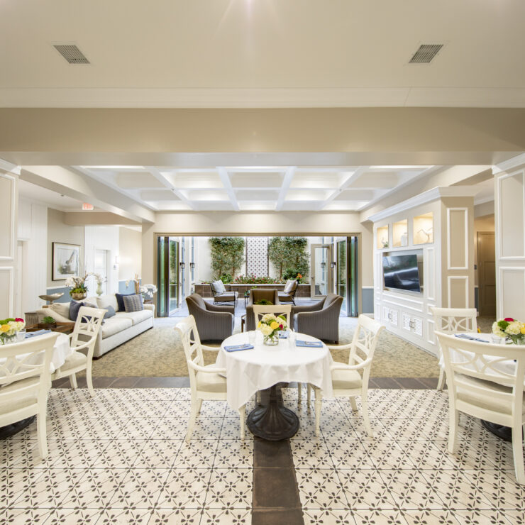 Bright communal dining and seating area with fresh flowers and open access to a garden patio.