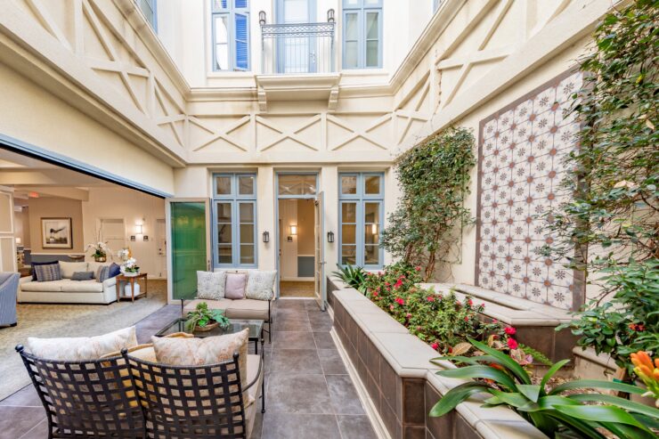 Bright, inviting courtyard seating area with lush plants and easy access to comfortable indoor lounge spaces.