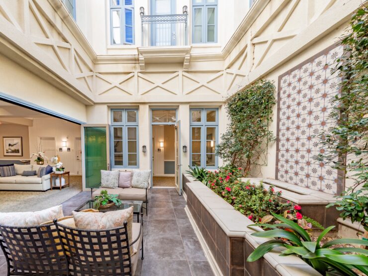 Bright, inviting courtyard seating area with lush plants and easy access to comfortable indoor lounge spaces.