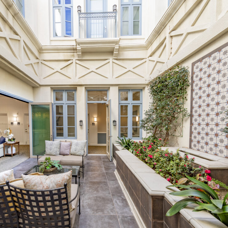 Bright, inviting courtyard seating area with lush plants and easy access to comfortable indoor lounge spaces.