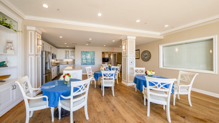 Bright dining area with blue tablecloths, fresh flowers, and comfortable seating for residents.