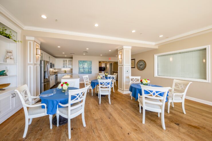 Bright dining area with blue tablecloths, fresh flowers, and comfortable seating for residents.