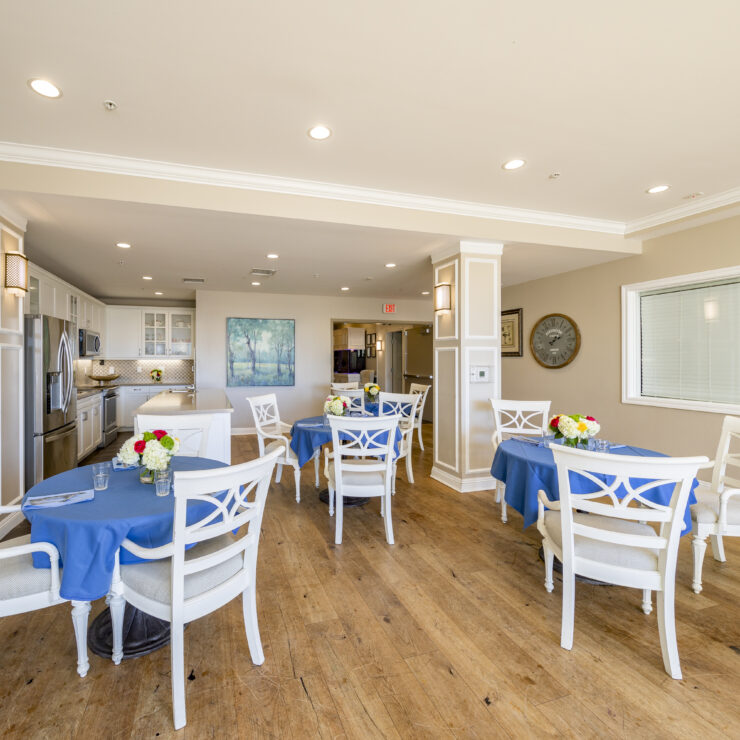 Bright dining area with blue tablecloths, fresh flowers, and comfortable seating for residents.