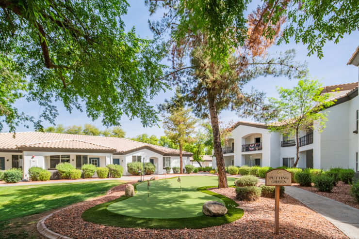 Well-maintained putting green surrounded by trees and comfortable retirement home buildings.