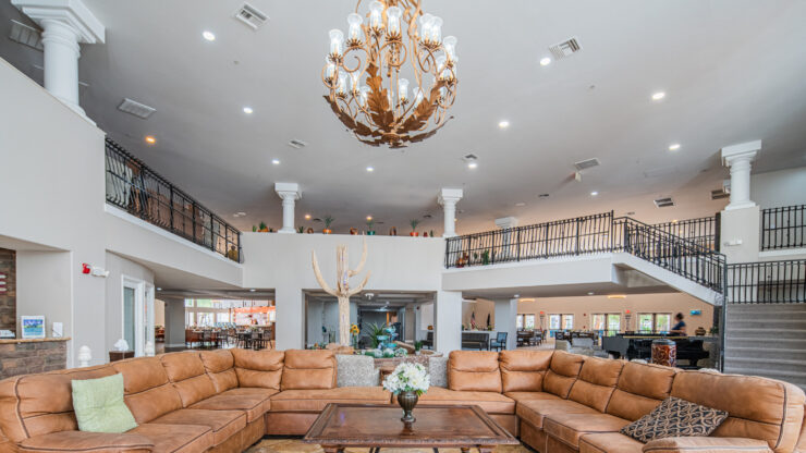 Spacious living area with comfortable seating, elegant chandelier, and welcoming community atmosphere.