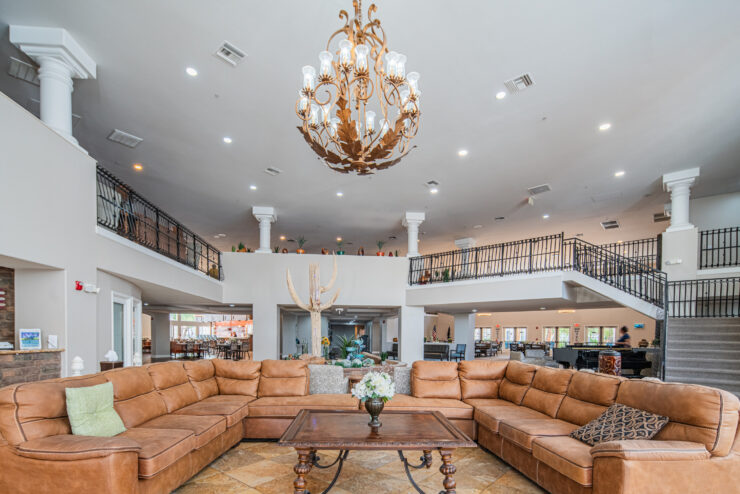 Spacious living area with comfortable seating, elegant chandelier, and welcoming community atmosphere.