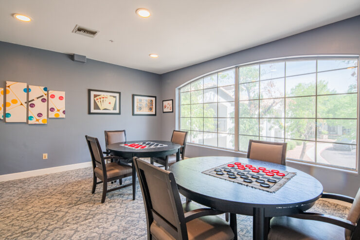Bright game room with large windows, round tables, and inviting seating for social activities.