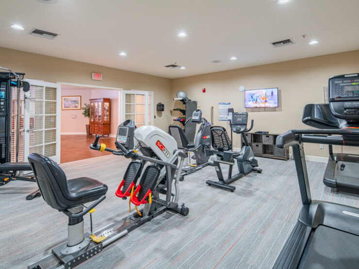 Bright, well-equipped fitness room with exercise machines and a welcoming atmosphere for seniors.