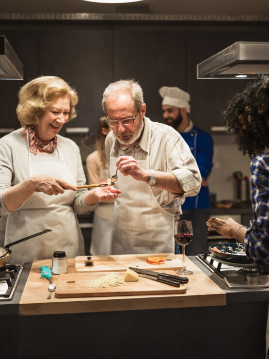 Seniors enjoying a group cooking activity, sharing laughter and good food in a warm kitchen.