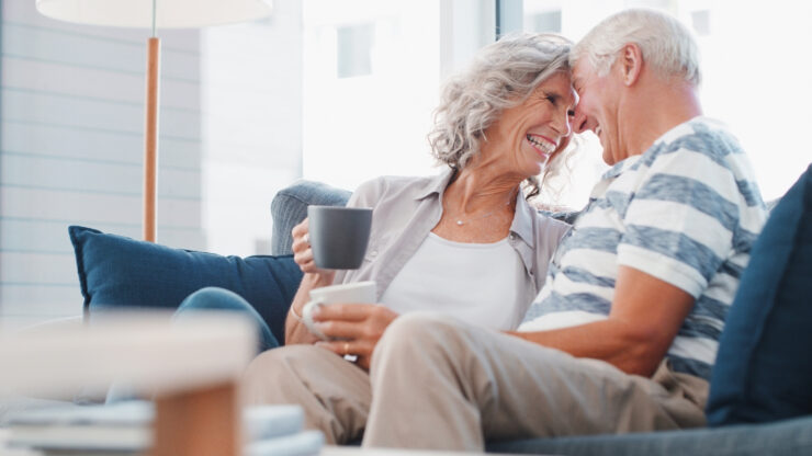 Senior couple sharing a warm moment and enjoying coffee together in a bright living room.