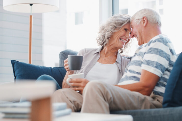 Senior couple sharing a warm moment and enjoying coffee together in a bright living room.