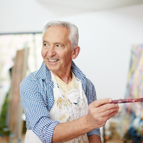 Senior man enjoying painting in a bright, welcoming art studio at a retirement community.