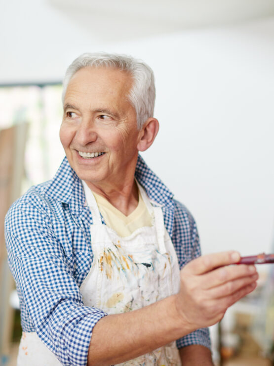 Senior man enjoying painting in a bright, welcoming art studio at a retirement community.