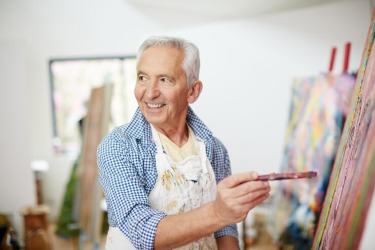 Senior man enjoying painting in a bright, welcoming art studio at a retirement community.