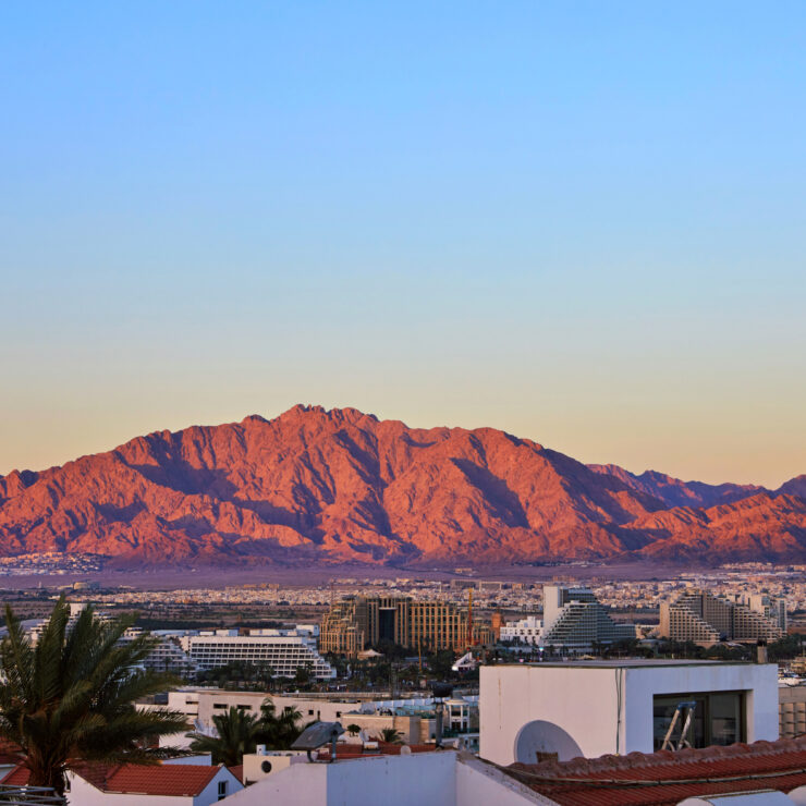 Sunlit mountain backdrop overlooking a peaceful town and waterfront, inspiring calm and connection.