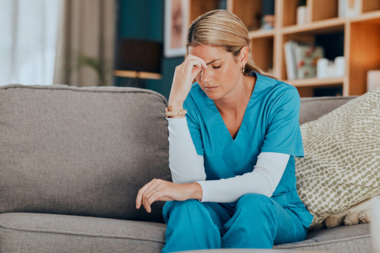 Healthcare professional taking a quiet moment of reflection in a warm, inviting living space.