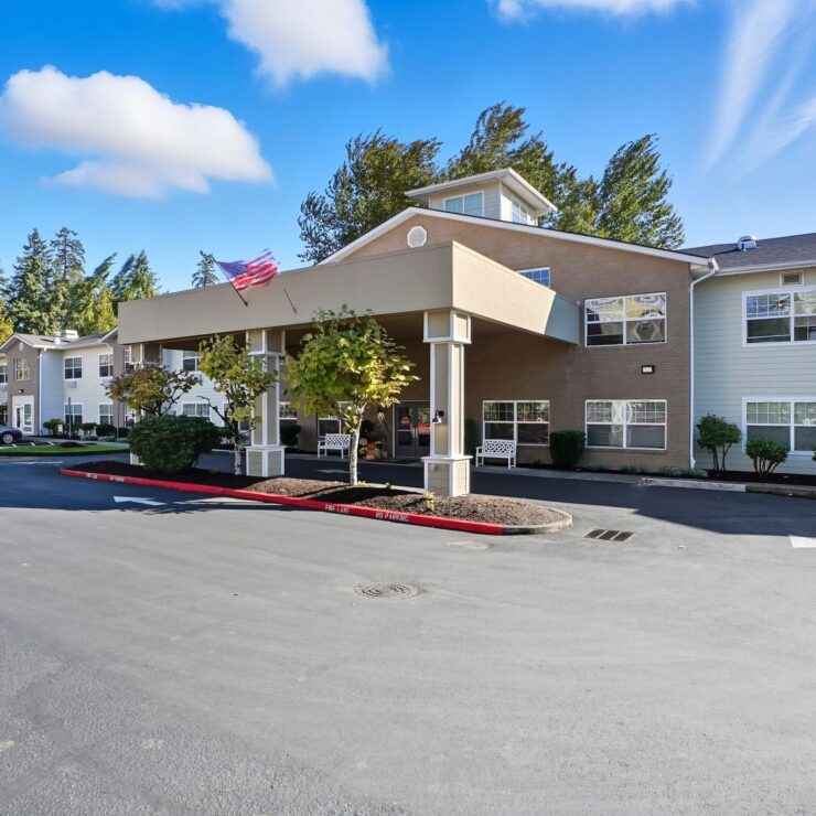 Well-maintained retirement community entrance with benches, trees, and clear blue skies.