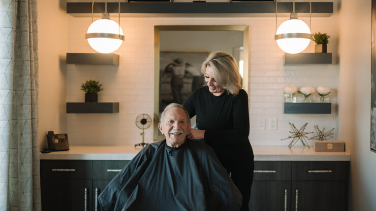 Senior man enjoying a friendly haircut in a warm, inviting salon space at the retirement home.
