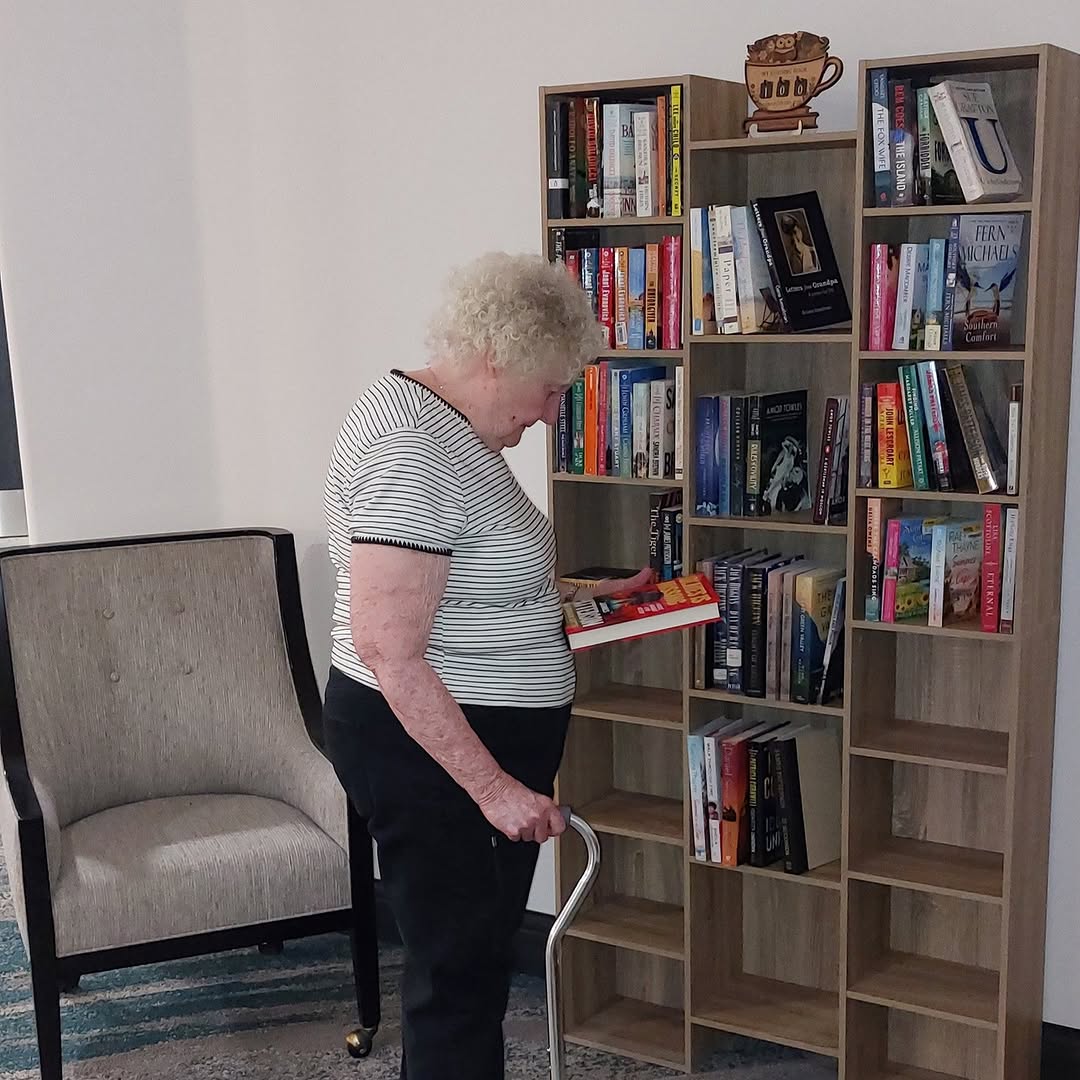 Mary, “checks out” a book from our library book nook expansion! Put together by other residents, Frank K. and Barbara B.