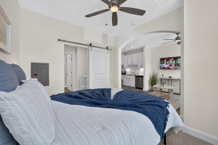 Bright, inviting bedroom with modern ceiling fan and open view into a comfortable living area.