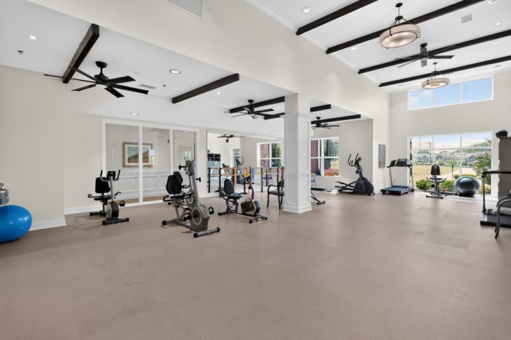Bright, spacious fitness room with modern equipment and large windows overlooking landscaped grounds