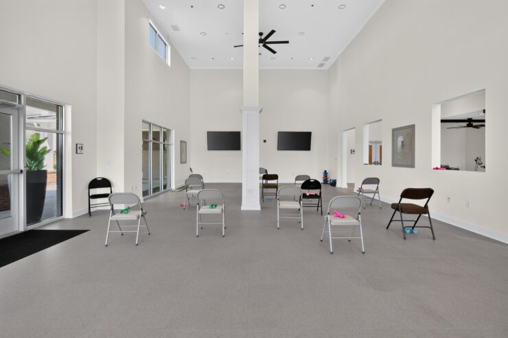 Bright, spacious activity room with chairs and light weights set for group fitness and socializing.