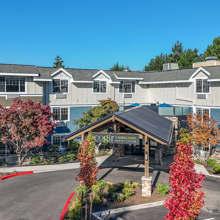 Senior living community entrance with landscaped gardens and vibrant autumn trees.