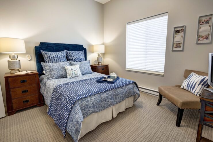 Well-lit bedroom with inviting blue bedding, soft lighting, and personalized touches for comfort.