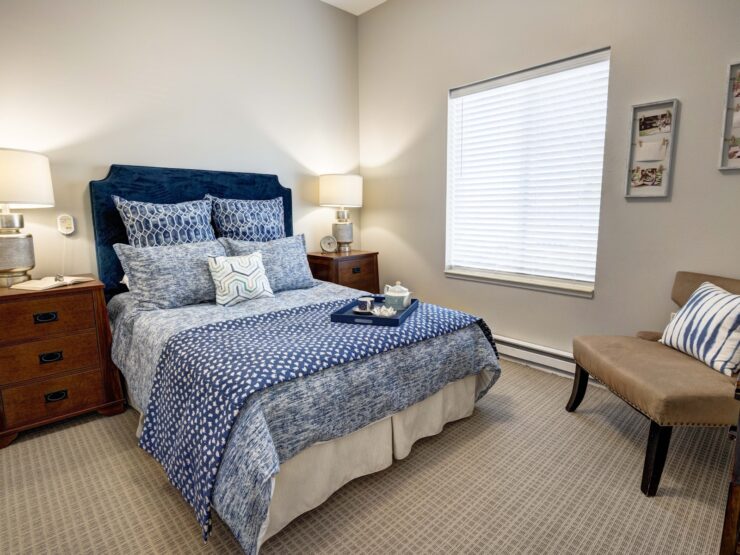 Well-lit bedroom with inviting blue bedding, soft lighting, and personalized touches for comfort.