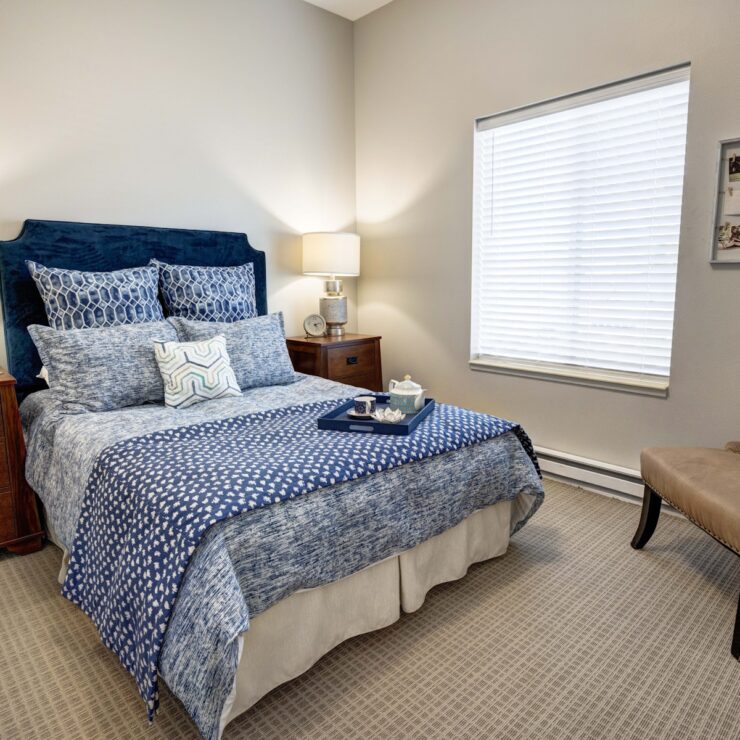 Well-lit bedroom with inviting blue bedding, soft lighting, and personalized touches for comfort.