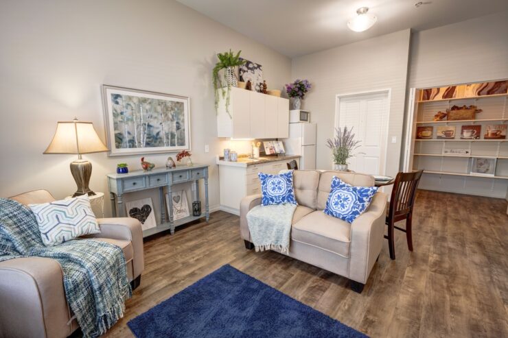 Well-lit living space with comfortable seating, decorative accents, and a welcoming kitchen area.