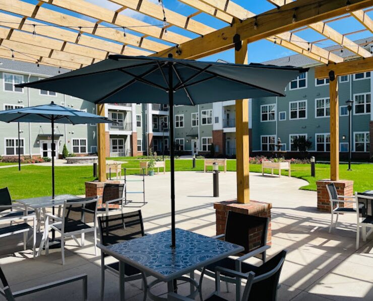 Shaded patio seating with umbrellas under a pergola in a peaceful community courtyard.