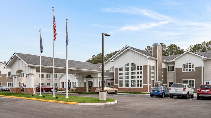 Well-maintained retirement community with welcoming entrance and ample parking under a clear sky.