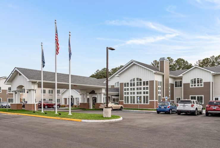 Well-maintained retirement community with welcoming entrance and ample parking under a clear sky.