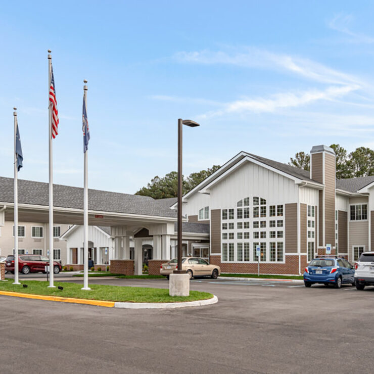 Well-maintained retirement community with welcoming entrance and ample parking under a clear sky.