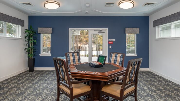Bright communal game room with a wood table, comfortable chairs, and access to a patio area.