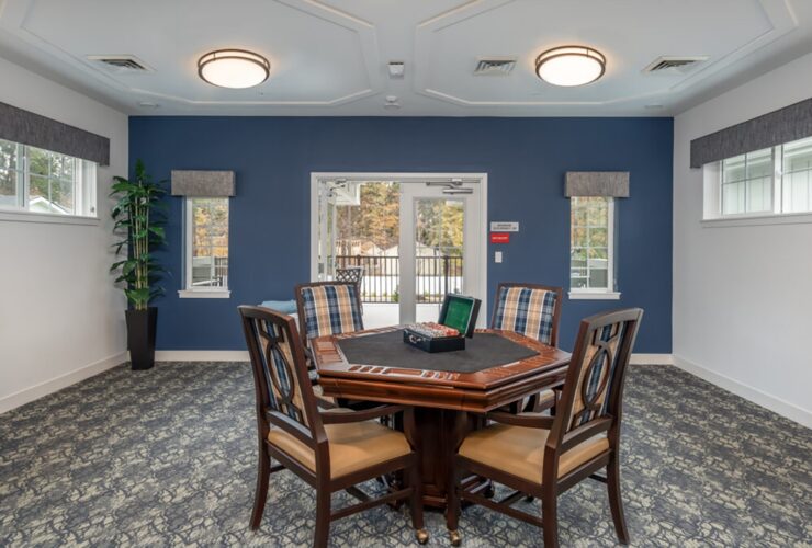 Bright communal game room with a wood table, comfortable chairs, and access to a patio area.
