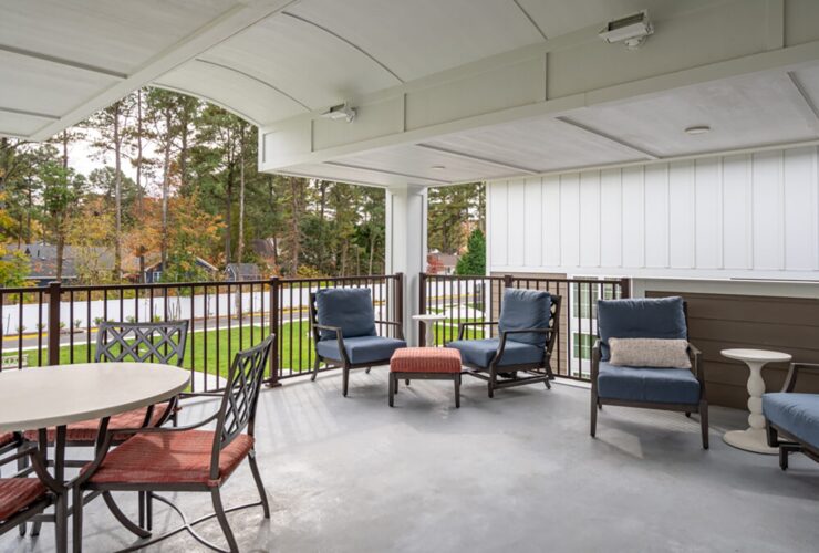 Spacious covered patio with comfortable seating and a peaceful view of trees and green lawn.